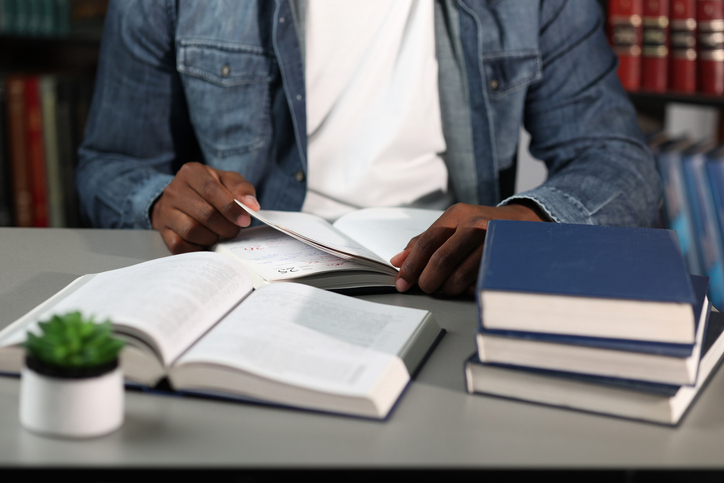 Black businessman holding book in denim shirt working at desk in modern office