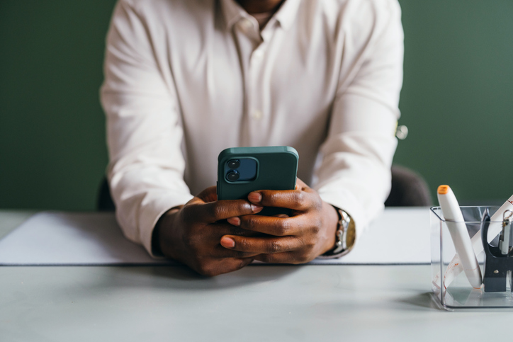 Professional in White Shirt Using Smartphone at Desk