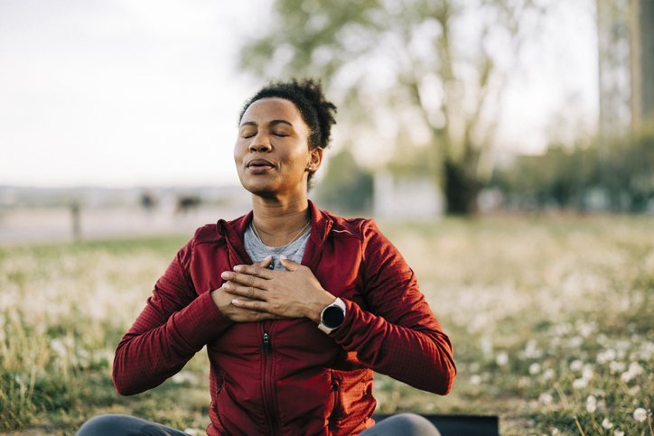 Black woman, breath and hand on chest, for meditation and wellness being peaceful to relax. Bokeh, African American female and lady outdoor, in nature and being calm for breathing exercise and health