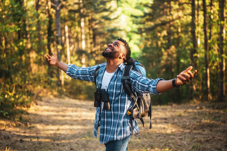 low cost ways to maintain mental health - pictured is a Hiker with arms raised enjoys in nature