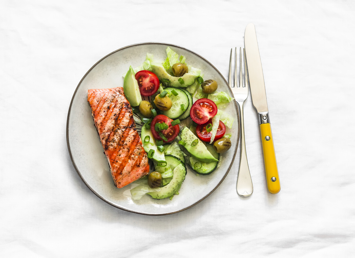 fatty acid - Healthy delicious lunch, dinner - grilled salmon and avocado, cherry tomatoes, cucumber, olives, iceberg lettuce on a light background, top view