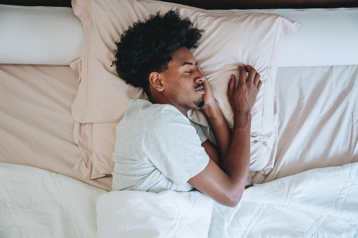 A young man sleeping on the bed in the bedroom