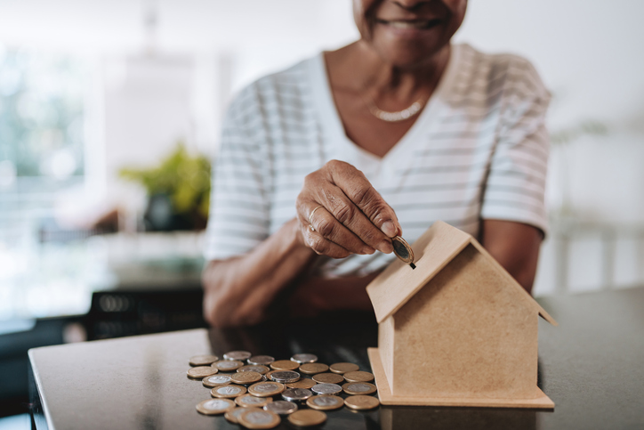 old woman - Senior woman putting coins into piggy bank