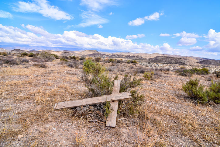 christianity in saudia arabia - A wooden cross is laying on the ground in a desert