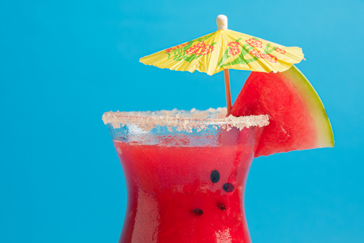 Breakfast Smoothies recipes - Watermelon juice on sea sand with blue background. Summer background.
