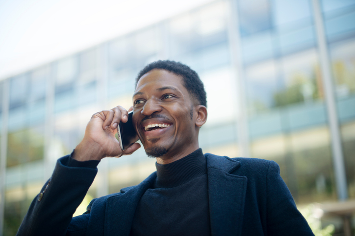 Business, man and phone call in city or thinking of good news, opportunity or happy networking with ideas or vision. Professional, African person listening on mobile, contact and travel in urban town