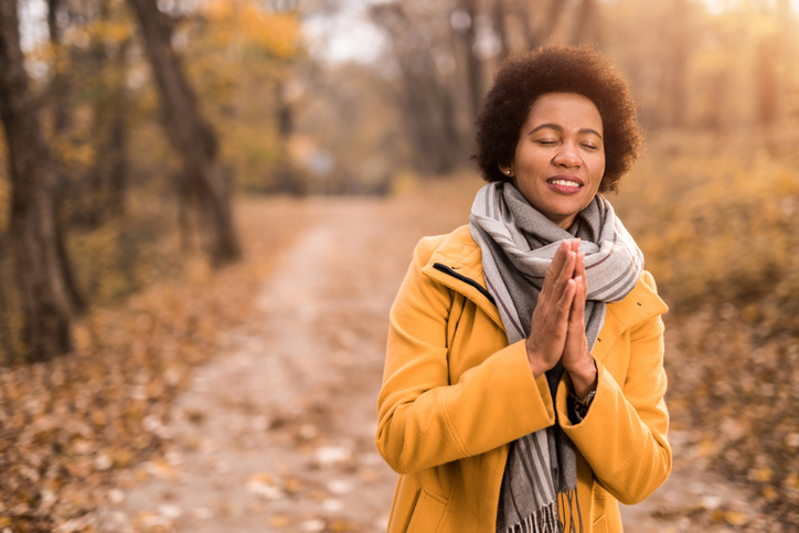 Tranquil mid adult woman meditating and doing yoga on a beautiful autumn day in nature.
