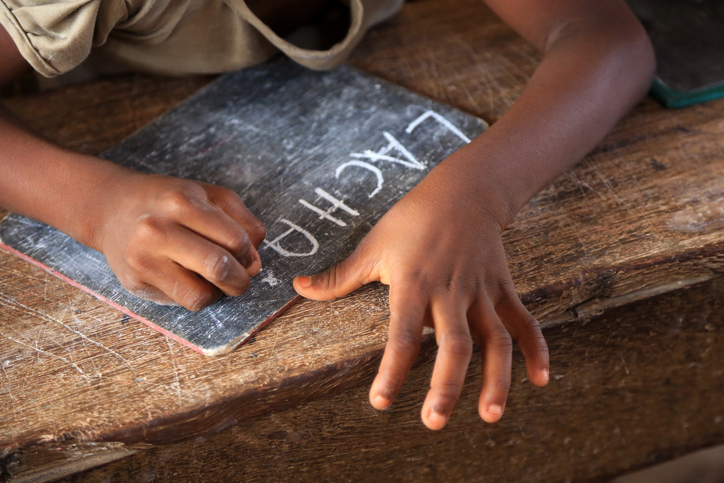 Primary school student writing in chalk on a blackboard. Spelling lessons. Lome. Togo. West Africa.