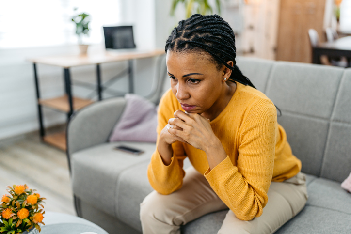 Sad Young Woman Sitting At Home On The Sofa