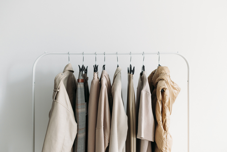fall capsule wardrobe - capsule clothes of beige coloron a rack. Closeup