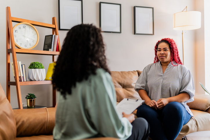 Mid adult patient woman talking with psychotherapist during therapy session at clinic