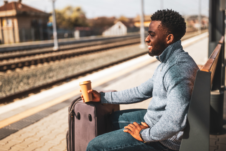 tips for solo travelers - Man with coffee and suitcase on train station
