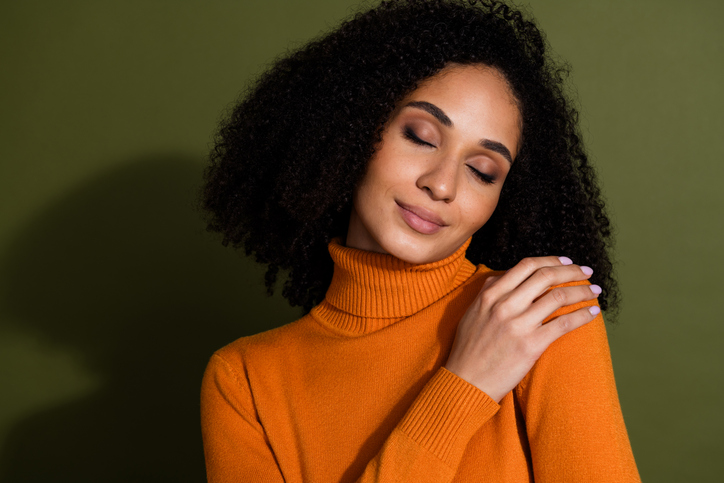 fall beauty trends - Photo of adorable cute girl wear orange jumper embracing herself empty space isolated khaki color background