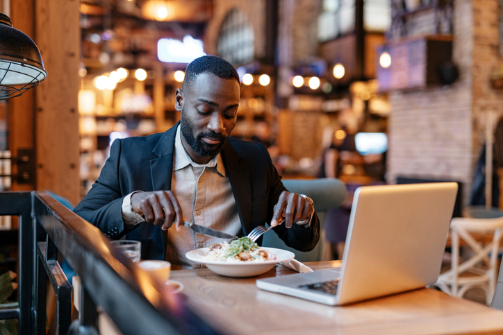 Why We Crave Spicy Sour Food - Focused man dining alone in a cafe with laptop.