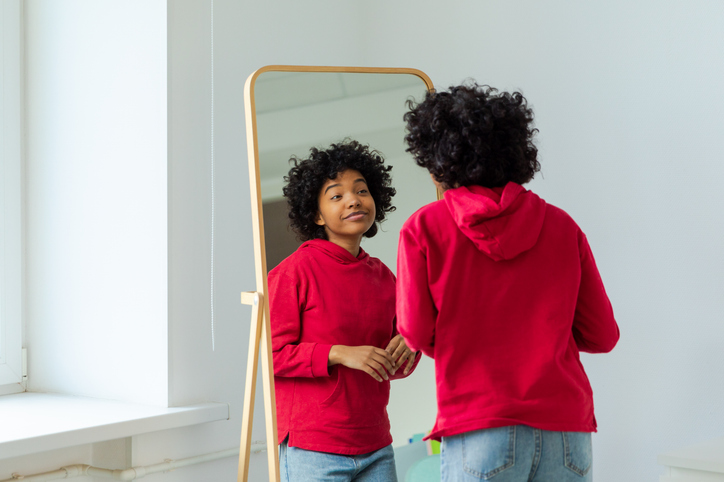Love yourself. Beautiful young smiling african american woman dancing enjoying her mirror reflection. Black lady looking at mirror looking confident and happy. Self love concept.