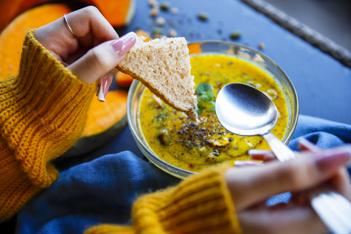 Young woman eating pumpkin broth