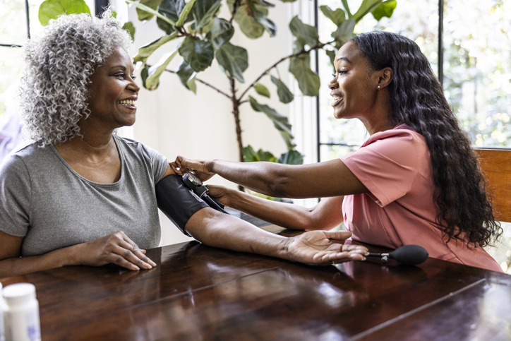 In home healthcare provider measuring senior woman's blood pressure in her home