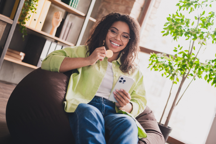 Portrait of young corporate lady hold cookie smart phone wear shirt loft interior business center office indoors