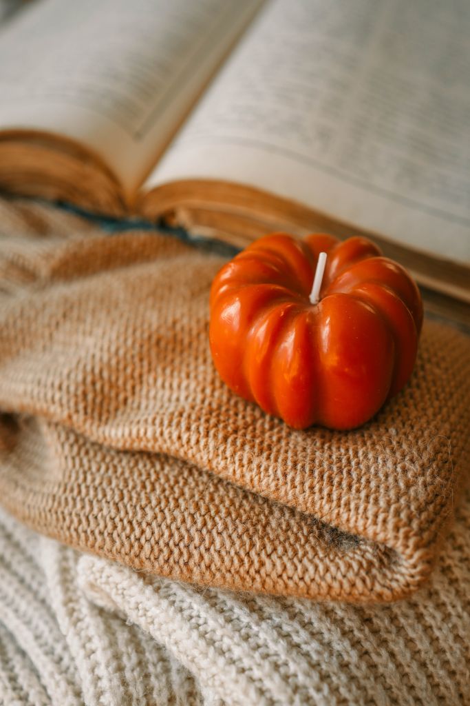 Autumn cozy decor, book, candle and sweater