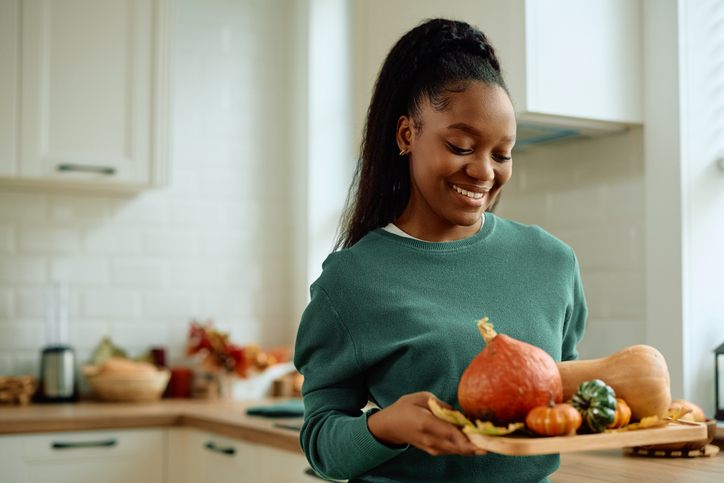 things you can do with pumpkins - Happy black woman with autumn decoration in the kitchen.