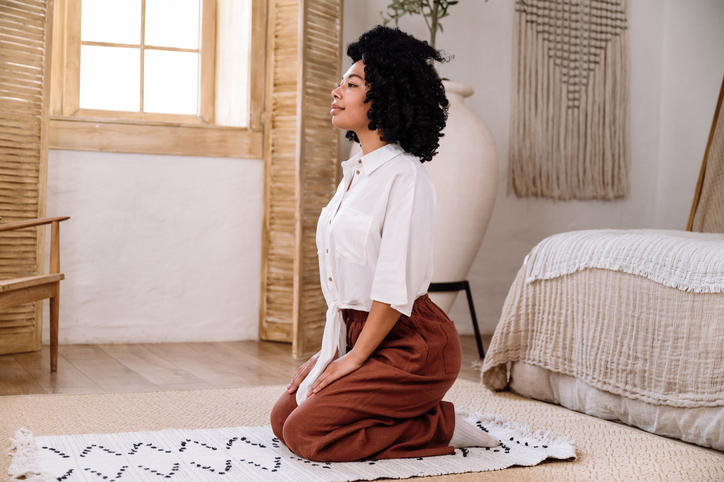 election prayer - woman sitting on rug and practicing yoga at home
