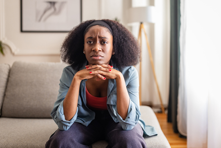 Worried woman sitting on sofa in cozy living room
