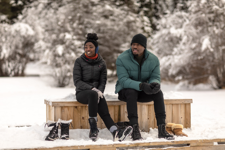 100 Activities to Try This Winter - Attractive couple sit at edge of frozen lake and contemplate ice-skating