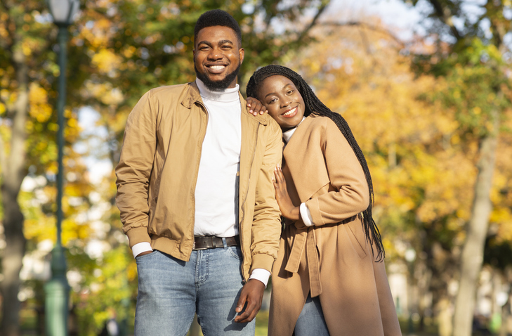Happy african american couple posing together over autumn park background