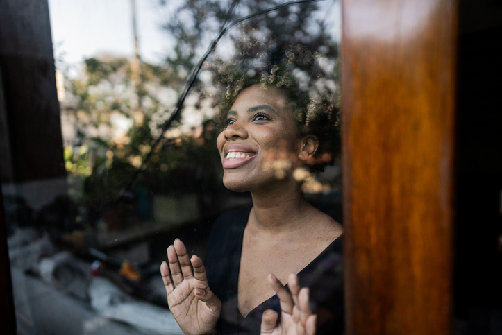 Young woman contemplating looking through the window at home
