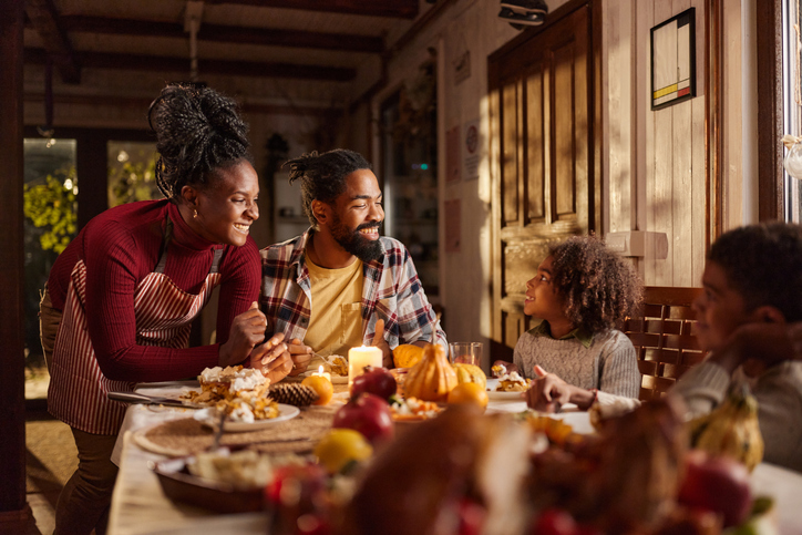 repurpose thanksgiving leftovers - Happy African American family talking during snack time in dining room.