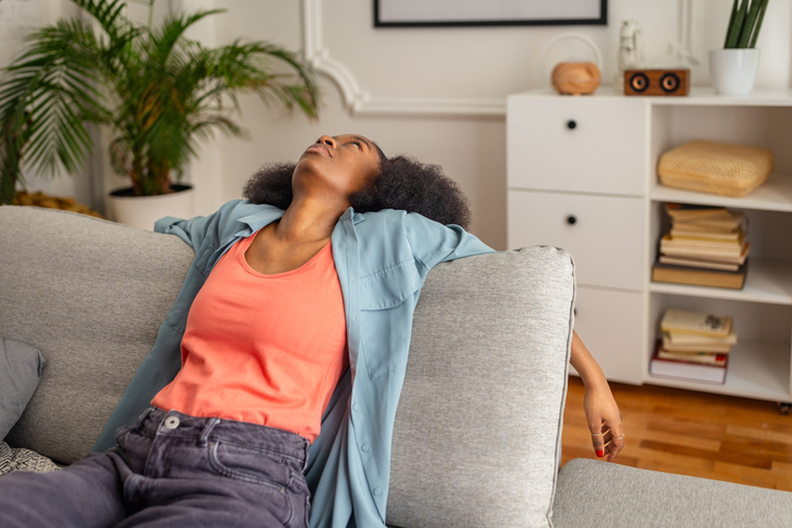 Relaxed individual reclining on a sofa in living room.