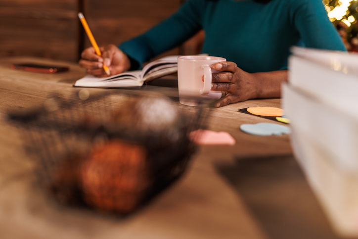 Young woman contemplating her New Year's resolutions and writing them in a diary