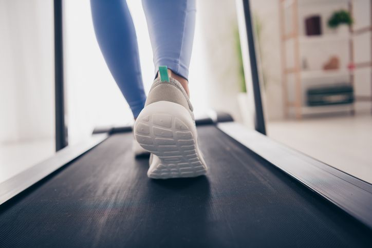 walking for depression - Close-up of a woman walking on treadmill in a modern home interior, wearing trendy sportswear and focusing on fitness and wellness