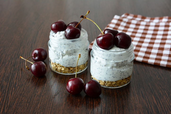some snack with granola, yogurt, chia, cherry and a checkered napkin