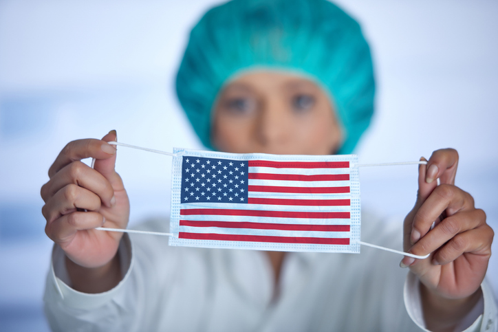 trump health policies - Female doctor with surgical cap presenting mouthguard with american flag
