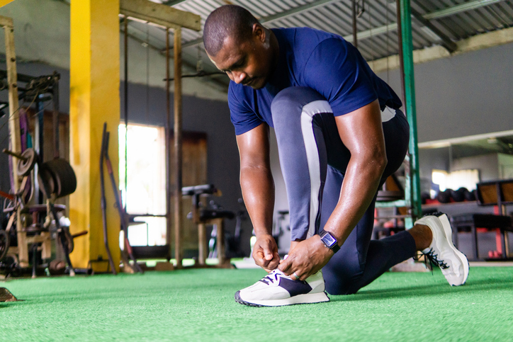 Determined male athlete tying shoelaces in gym, preparing for workout