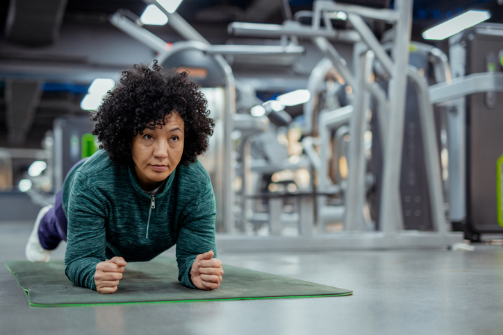 Fit Mature Female Athlete Demonstrating Core Strength with a Plank in Gym