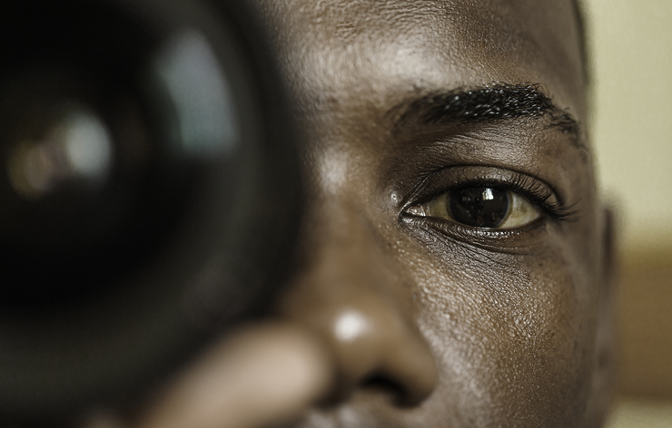Black photographer looking at camera through lens
