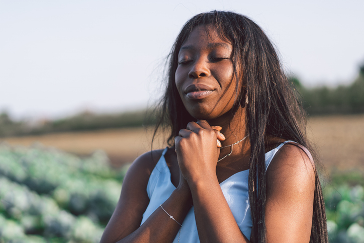 what is fasting - Girl closed her eyes, praying in a outdoors.