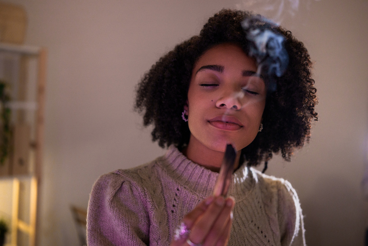 Serene young woman performing palo santo ritual at home