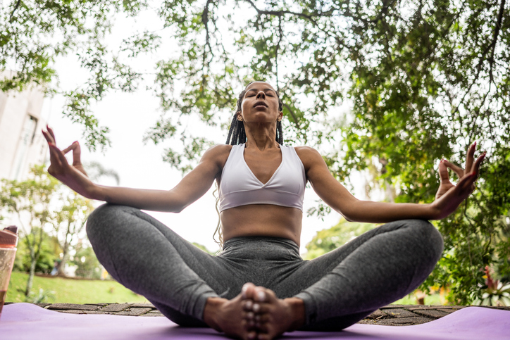 Mid adult woman meditating in a public park