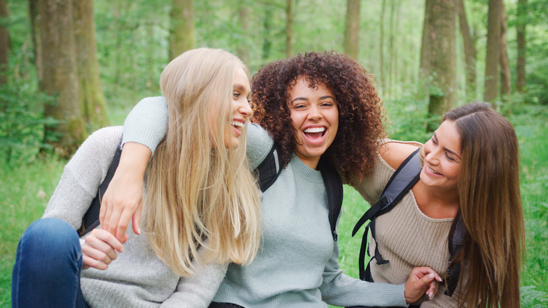 Portrait Of Smiling Multi-Cultural Group Of Female Friends Hiking Through Forest In UK Lake District
