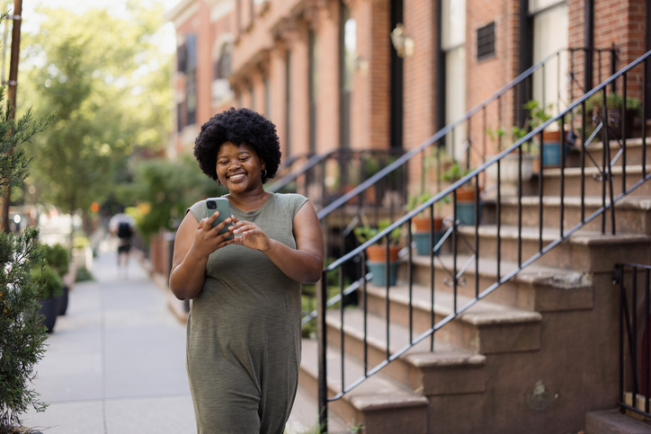 Woman Using Smartphone While Walking in an Urban Neighborhood