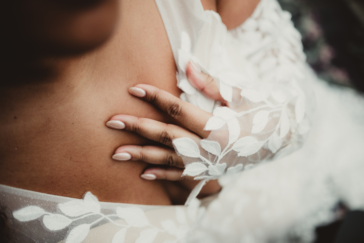 Bride in wedding dress with manicured hand by chest