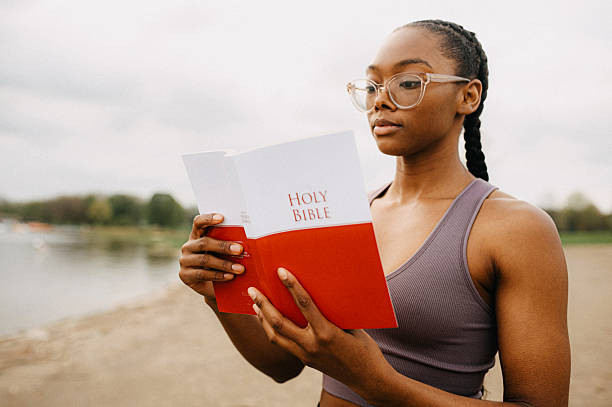 A young woman wearing glasses reads a Bible